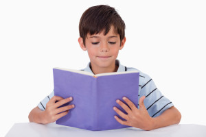 Focused boy reading a book against a white background
