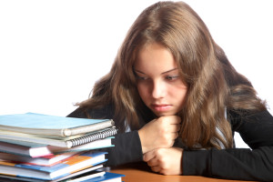 The girl-teenager looks at pile of books on a white background